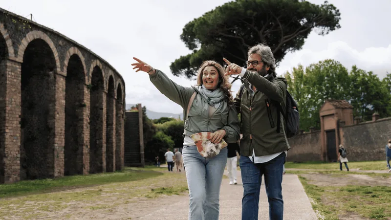 Couple pointing at the arches of the amphitheatre walls, the self-guided option among Pompeii tours from Rome by high-speed train, Italy